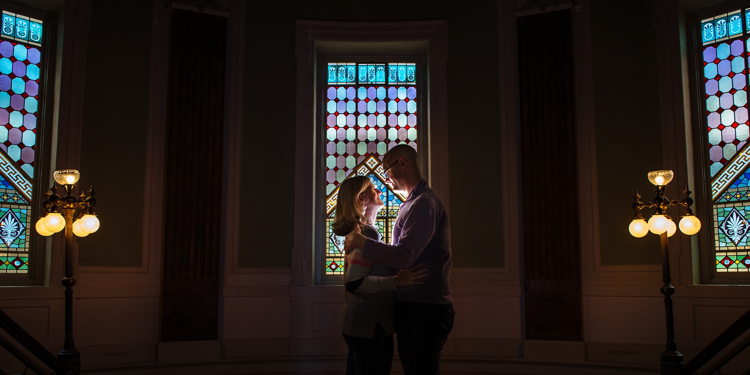 engaged couple standing in front of a stain glass window at the national gallery of art